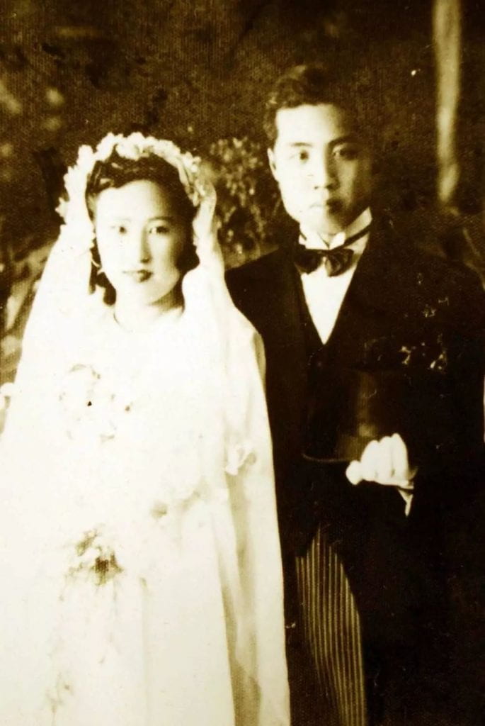 black and white photograph of a married man and woman on their wedding day wearing a bridal gown and suit