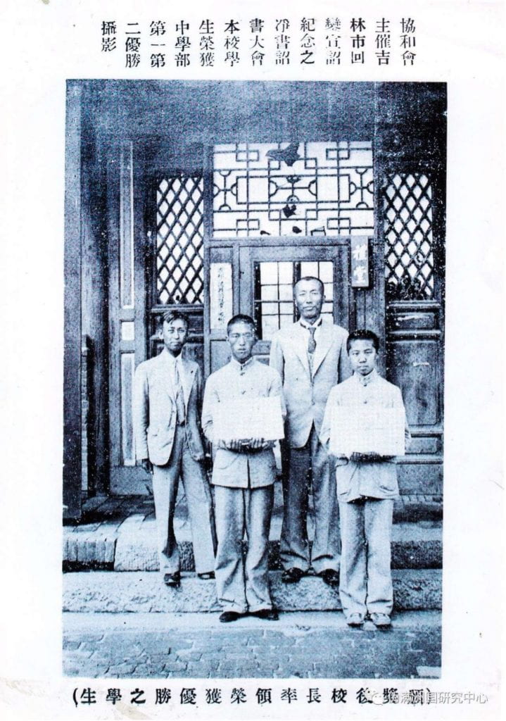 photograph of four men standing holding pieces of paper