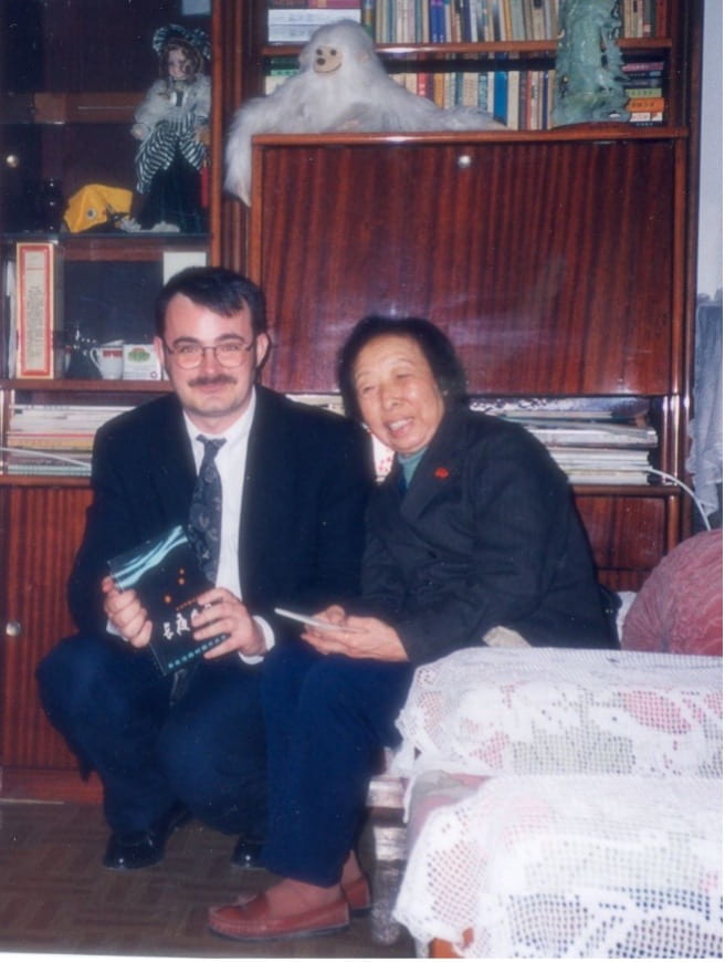 Photograph of a man and elderly woman sitting beside one another and smiling 