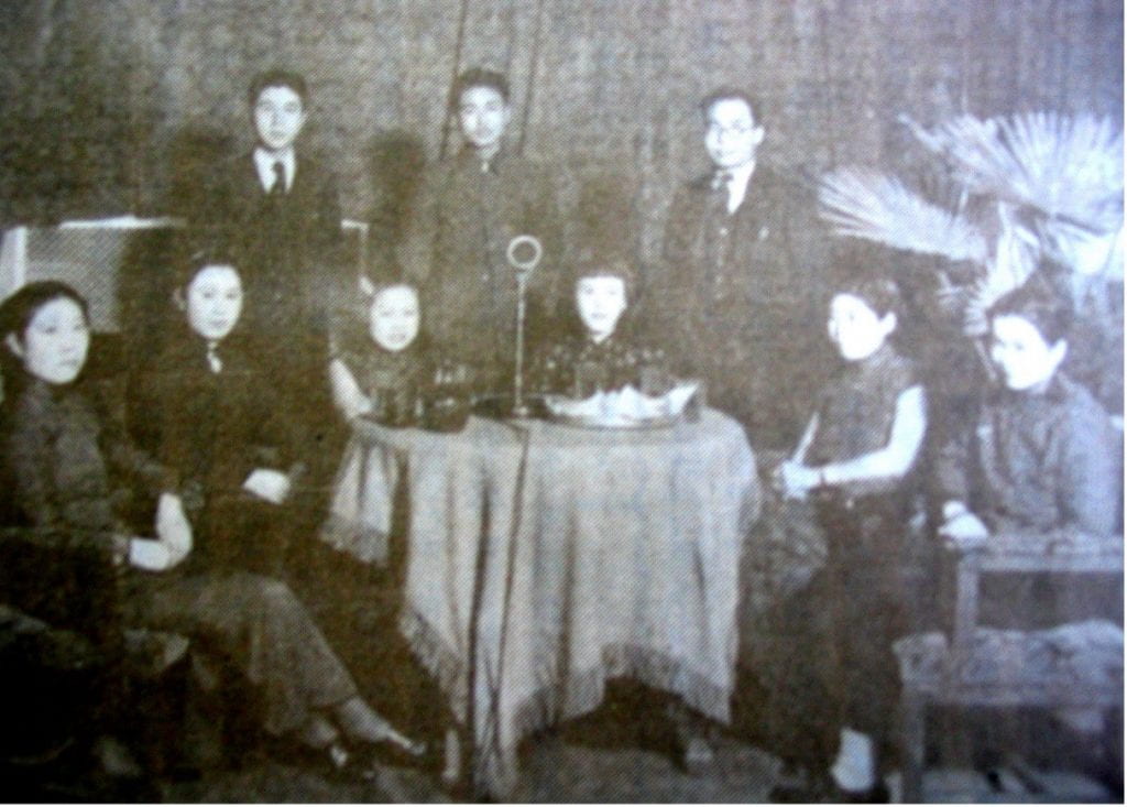 black and white image of a group of men and women sitting around a table