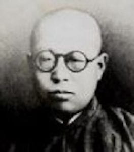 A portrait shot of a balding man wearing circular glasses