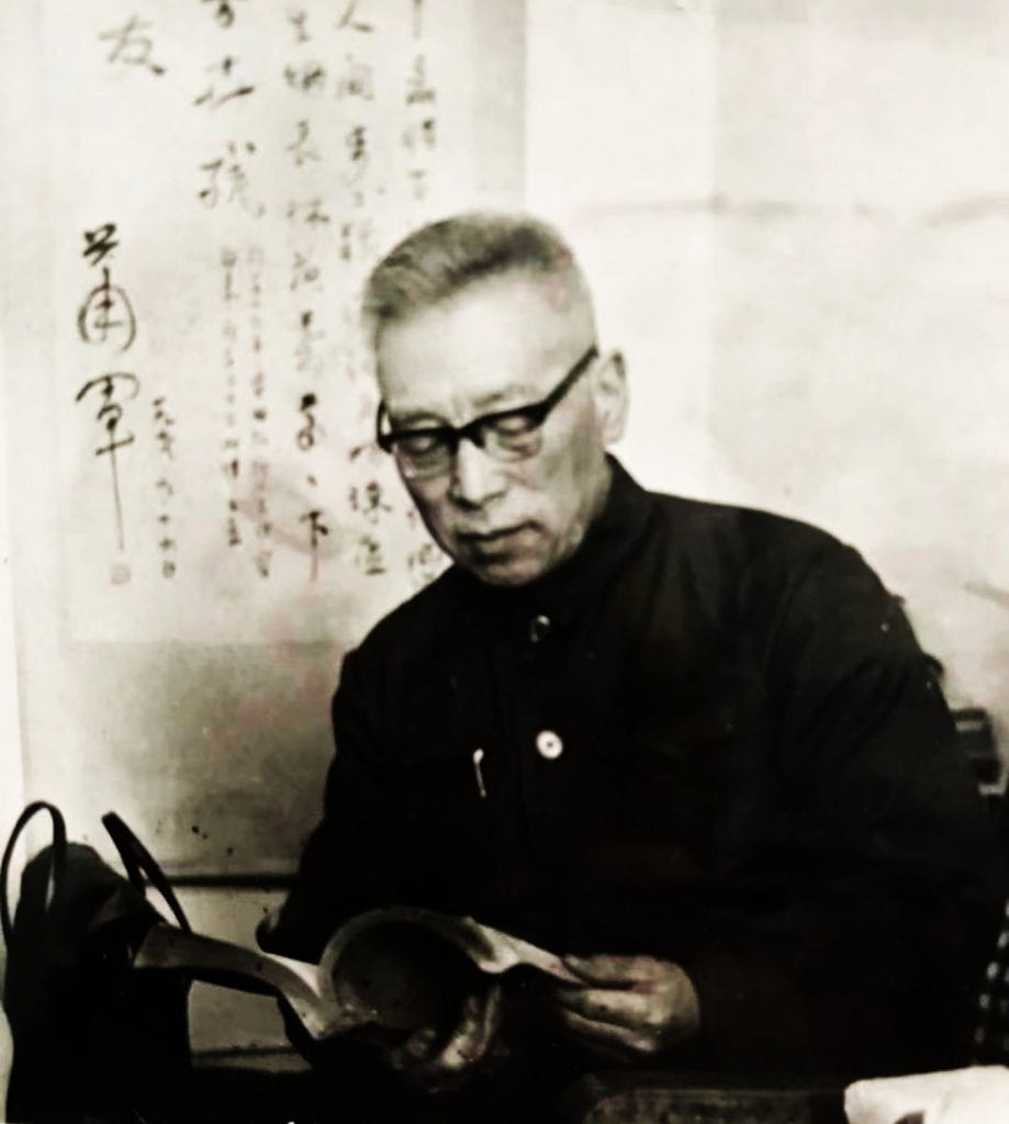black and white photograph of an elderly man with glasses reading a book