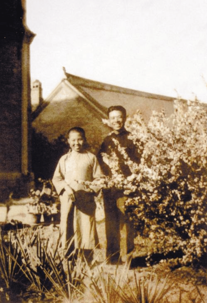 old photograph of two smiling boys outside surrounded by trees