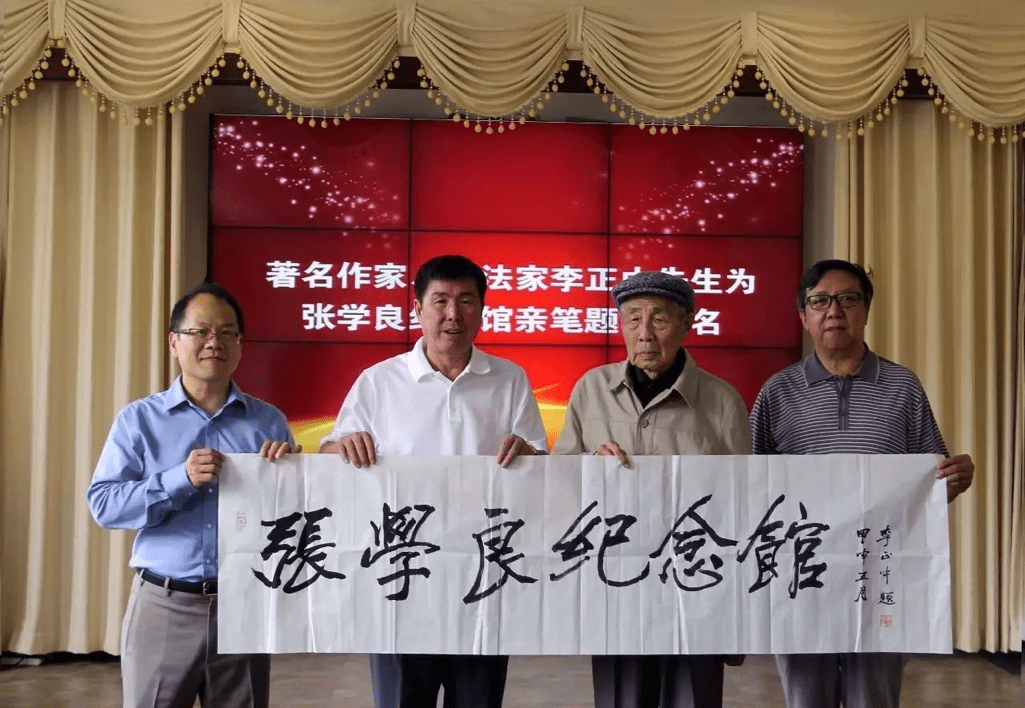 four men standing together and holding up a work of calligraphy
