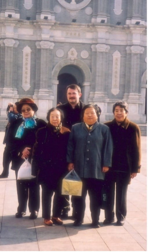 photo of four elderly women with a man posing in front of a building