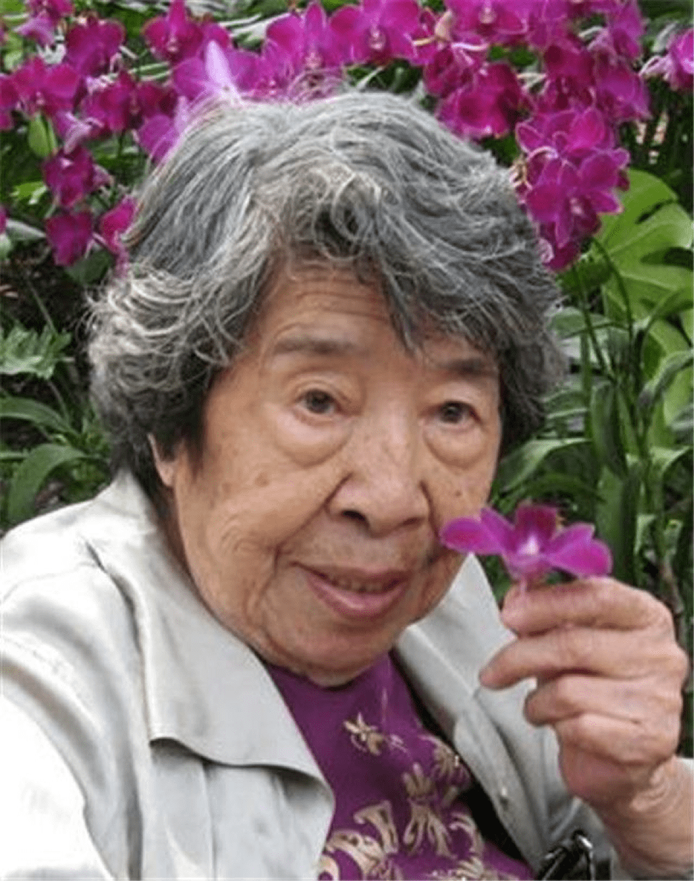 photo of an elderly woman holding purple flowers