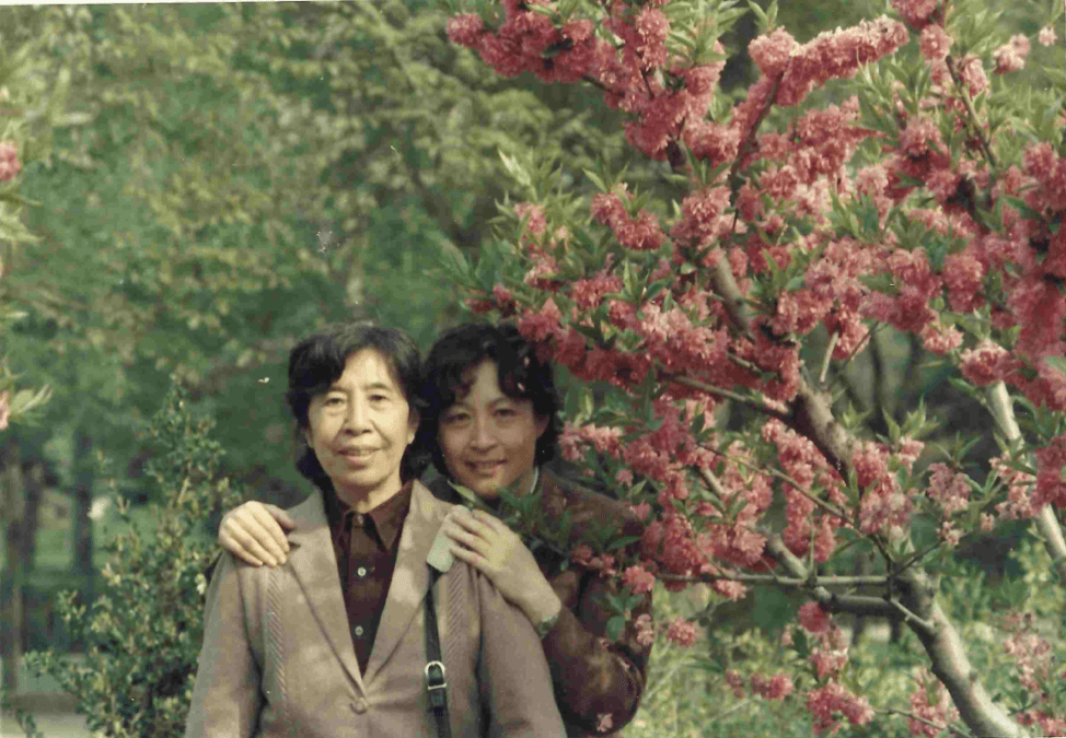 photograph of an elderly woman and a middle aged woman posing in front of trees