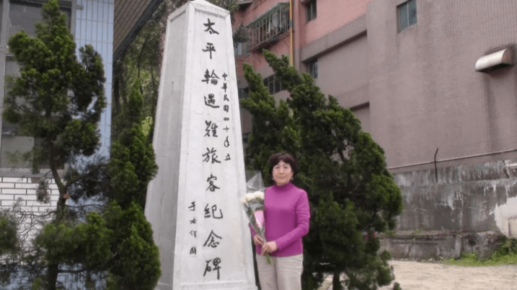 image of a woman holding flowers in front of a memorial