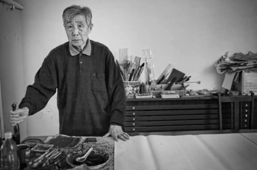 Li Zhengzhong at his calligraphy table with his supplies behind him
