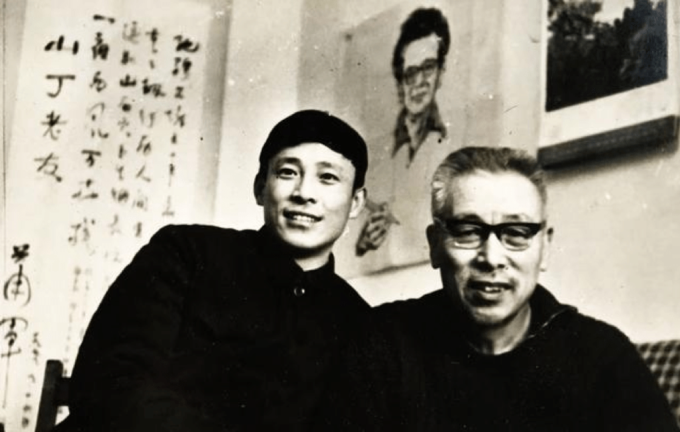 black and white photograph of two men smiling in front of works of calligraphy