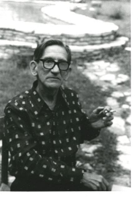 black and white photograph of a man with glasses smoking outside